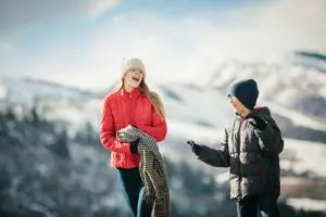 A brother and sister together outdoors in the winter, laughing.