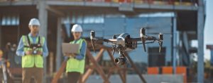 Two construction workers operate a survey drone on a work site.