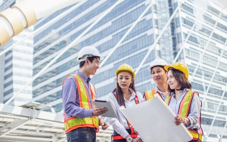 Group of people wearing hard hats look at plans together