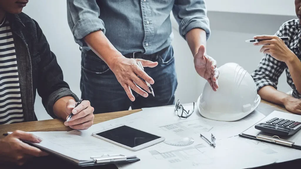 Civil Site Optimization for Utah Commercial Developments 8 people gathered around a table gesturing at some plans