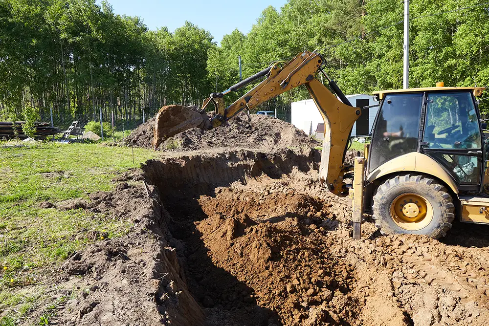 Navigating Septic System Design in Utah: A Comprehensive Guide to Permitting, Soil Testing, and Regulatory Approvals 1 Backhoe excavator digging a deep trench at a construction site, moving soil to prepare ground for foundation