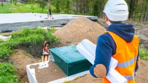 Septic tank near the foundation. Autonomous conolization. Builder is looking at a septic tank. Treatment facilities at a construction site.