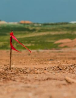 Metal survey peg with red flag on construction site.