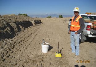 Engineer standing on a flat, brown, open land.