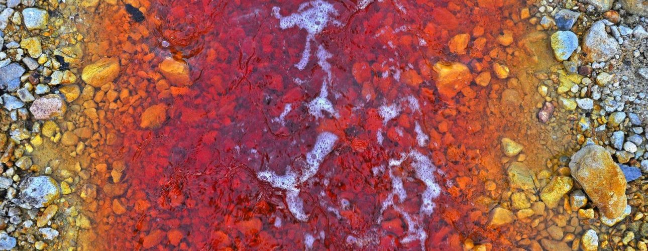 Red polluted water stream in Geamana, Rosia Montana, Romania